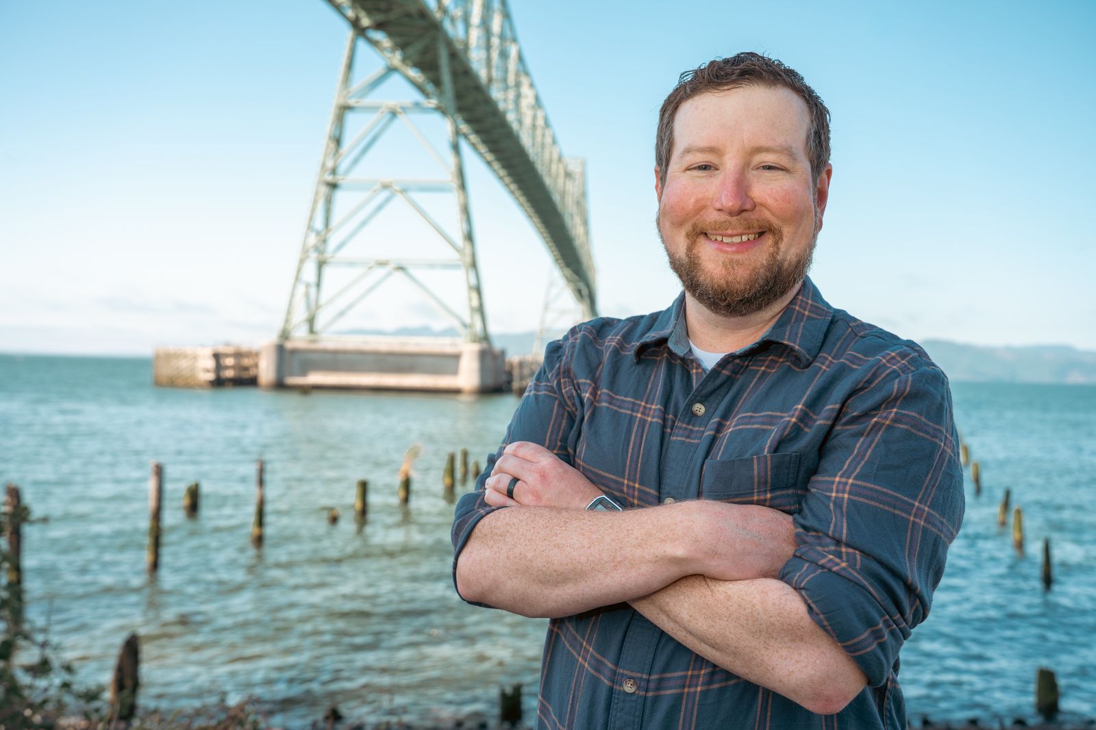 Andy Kipp standing on the Astoria waterfront with the Astoria-Megler Bridge behind him